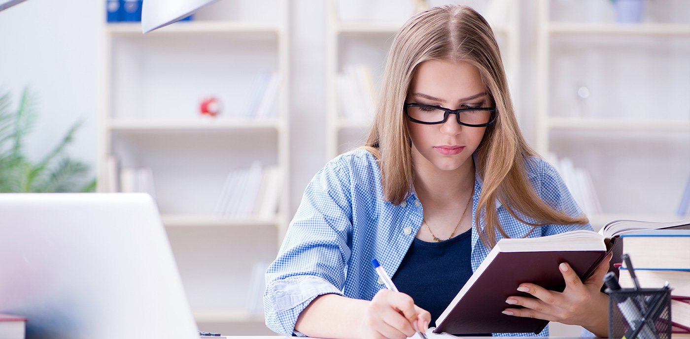 University graduate student in cap and gown celebrating with diploma at campus graduation ceremony with proud parents