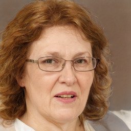 Professional headshot of young woman with blonde hair in elegant dress smiling warmly at camera
